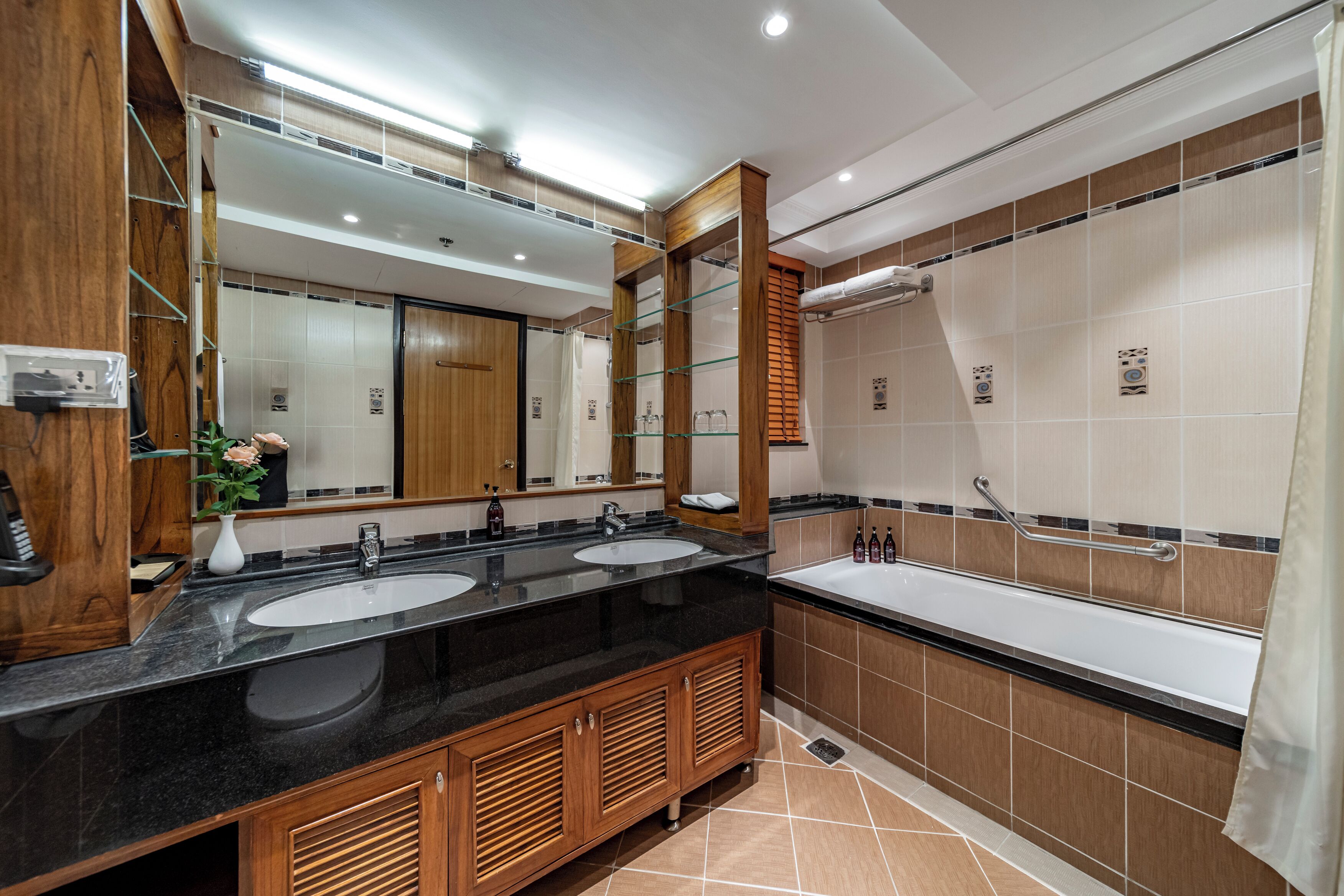 A modern bathroom with two sinks, a large mirror, and a bathtub.