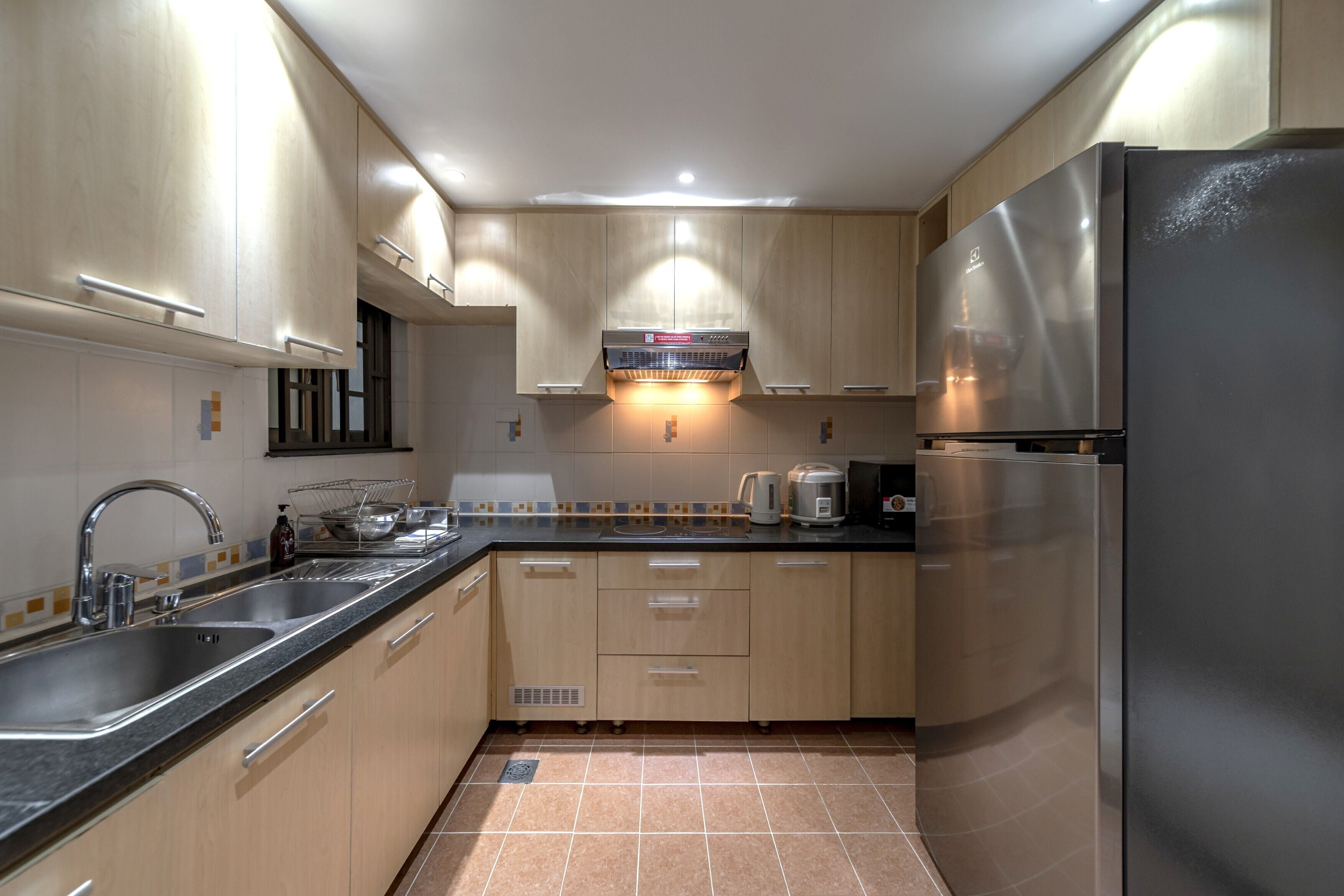 A modern kitchen with stainless steel appliances, wooden cabinets, and a black countertop.