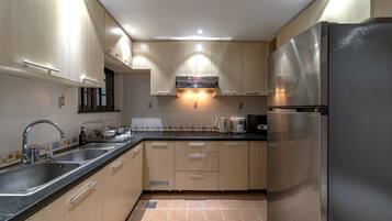 A modern kitchen with stainless steel appliances, wooden cabinets, and a black countertop.