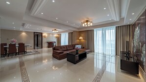 A spacious living area with a brown sofa, a coffee table, and a dining table with chairs.