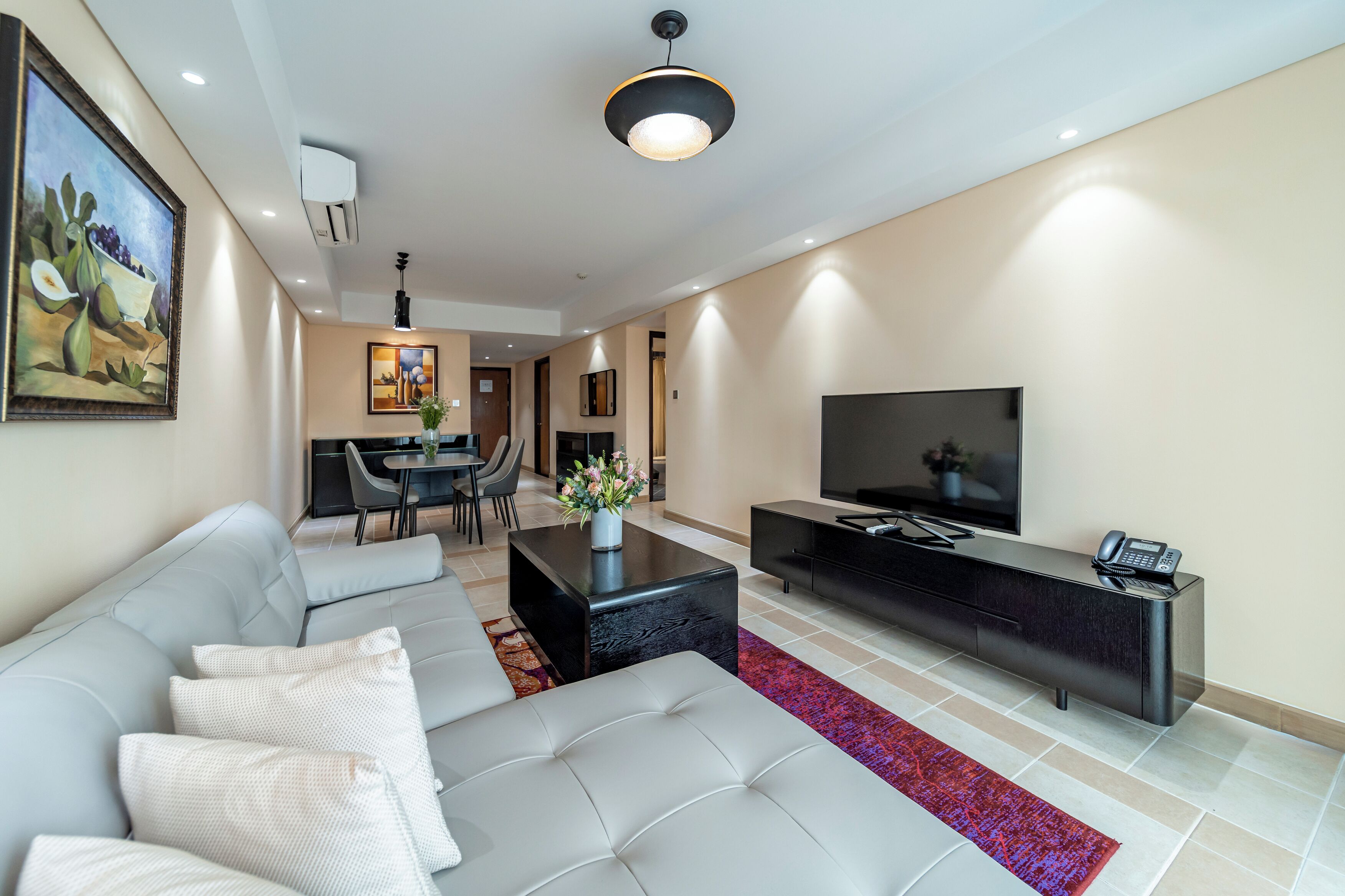 A modern living room with a grey sofa, black entertainment unit, and a flat-screen TV.