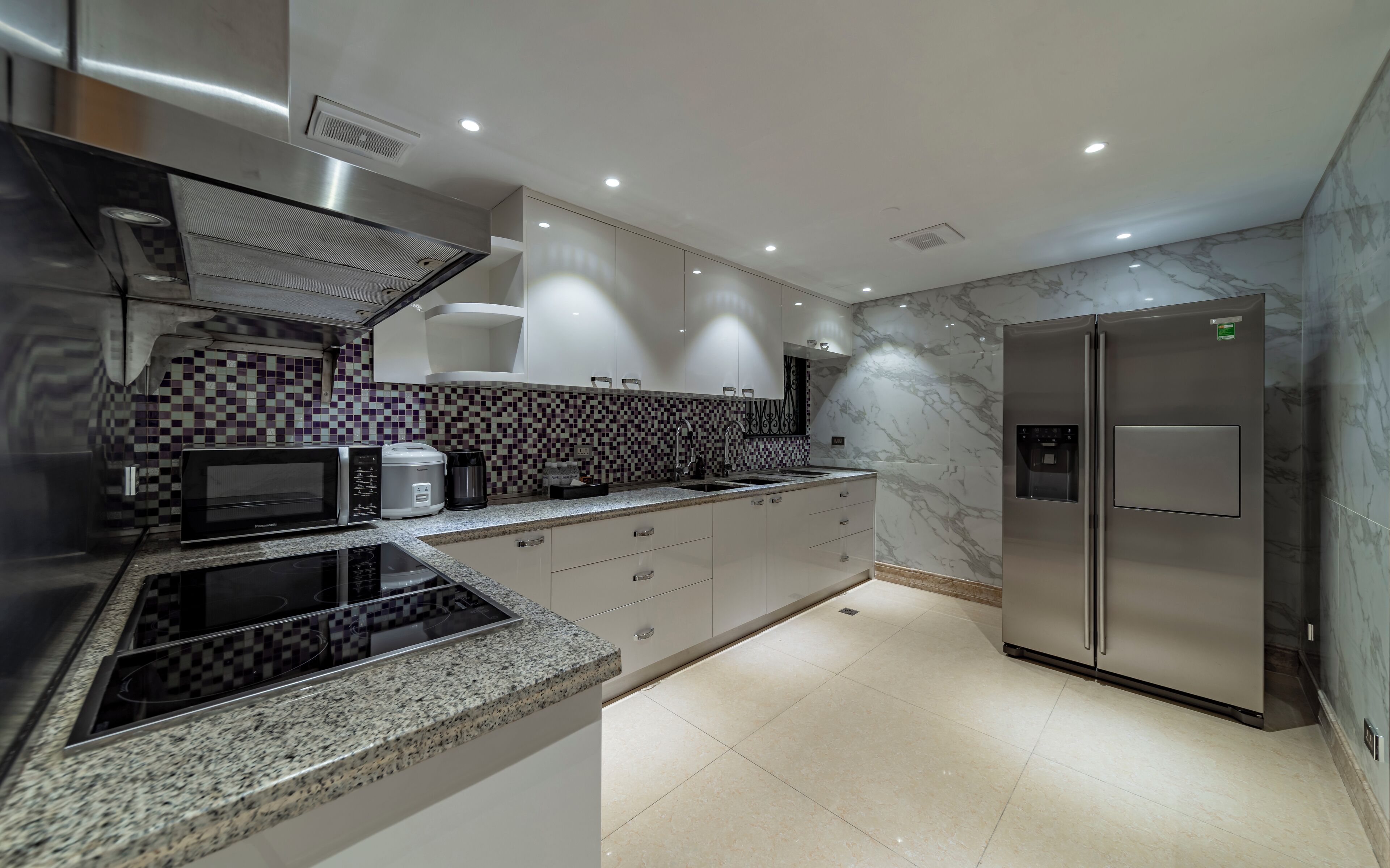Una cocina moderna con encimera de granito, electrodomésticos de acero inoxidable y salpicadero de mármol.