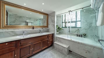 Un baño con tocador de mármol, un espejo grande, ducha con puertas de cristal y una planta en maceta.