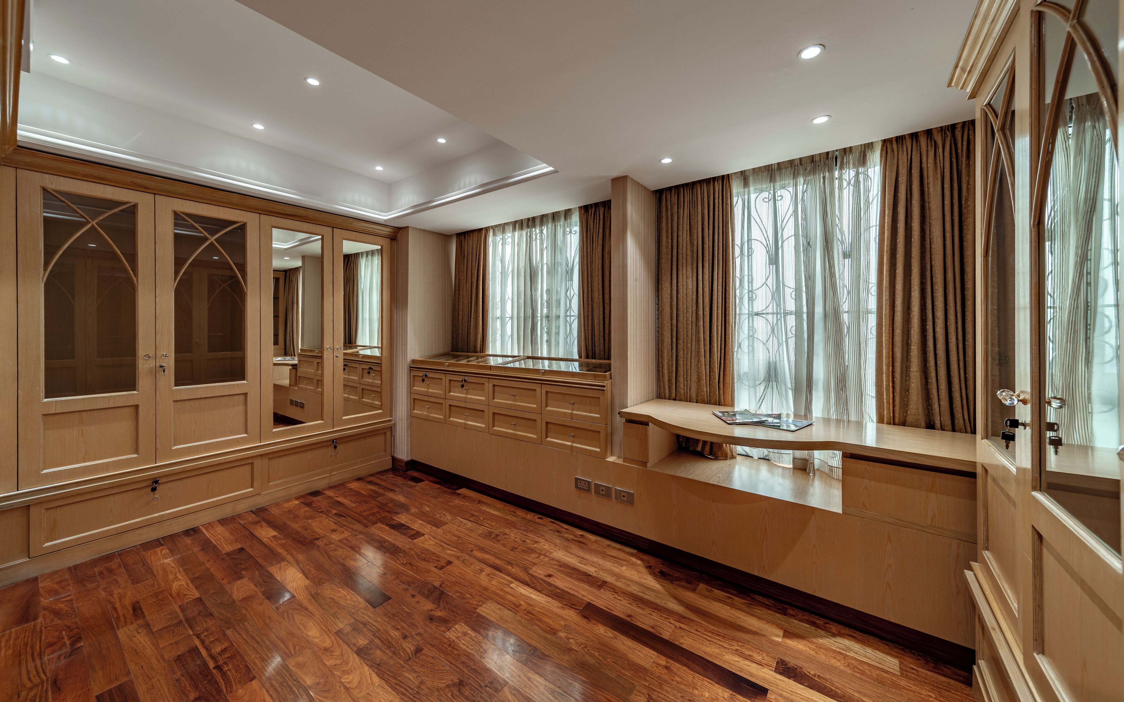 Una habitación amplia con suelo de madera, un espejo grande y un tocador con lavabo.