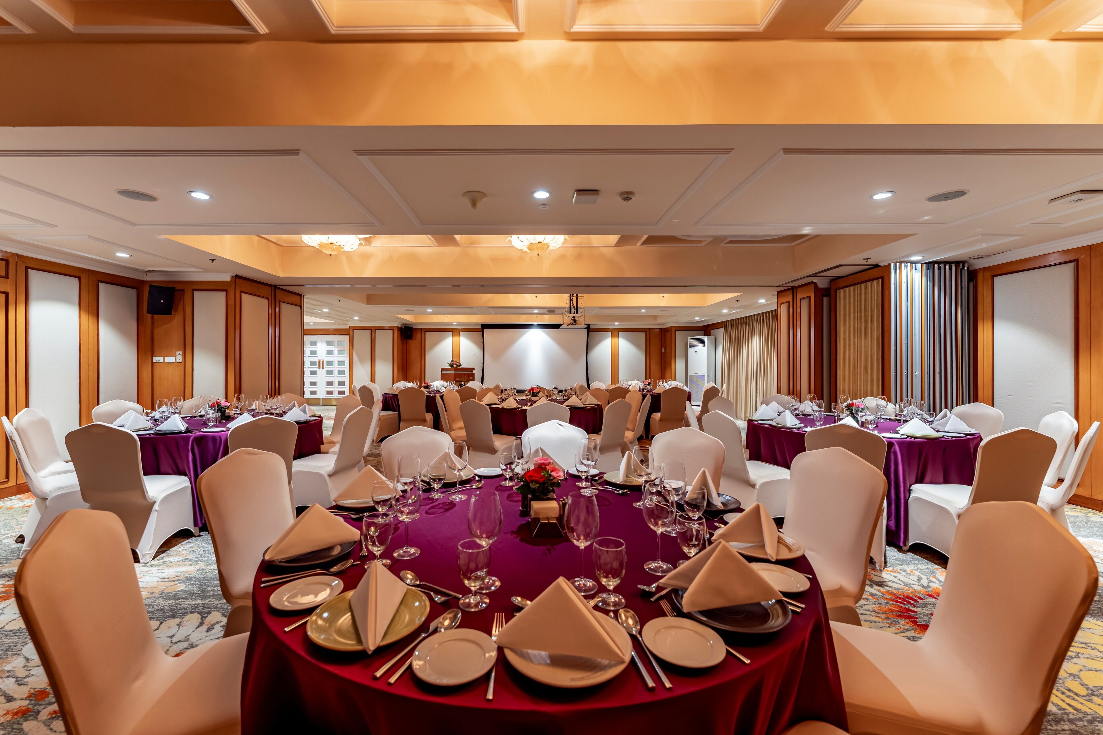 A banquet hall with round tables set for dining, equipped with chairs and table settings.