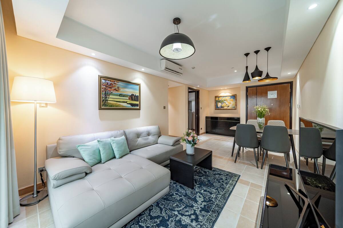 A modern living room with a sofa, coffee table, and dining area with chairs.