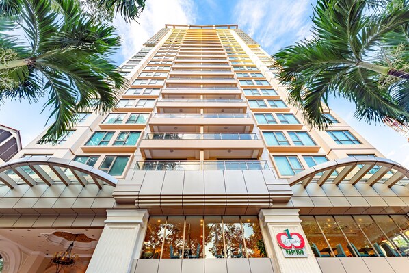 A high-rise hotel with multiple balconies, large windows, and a central atrium.