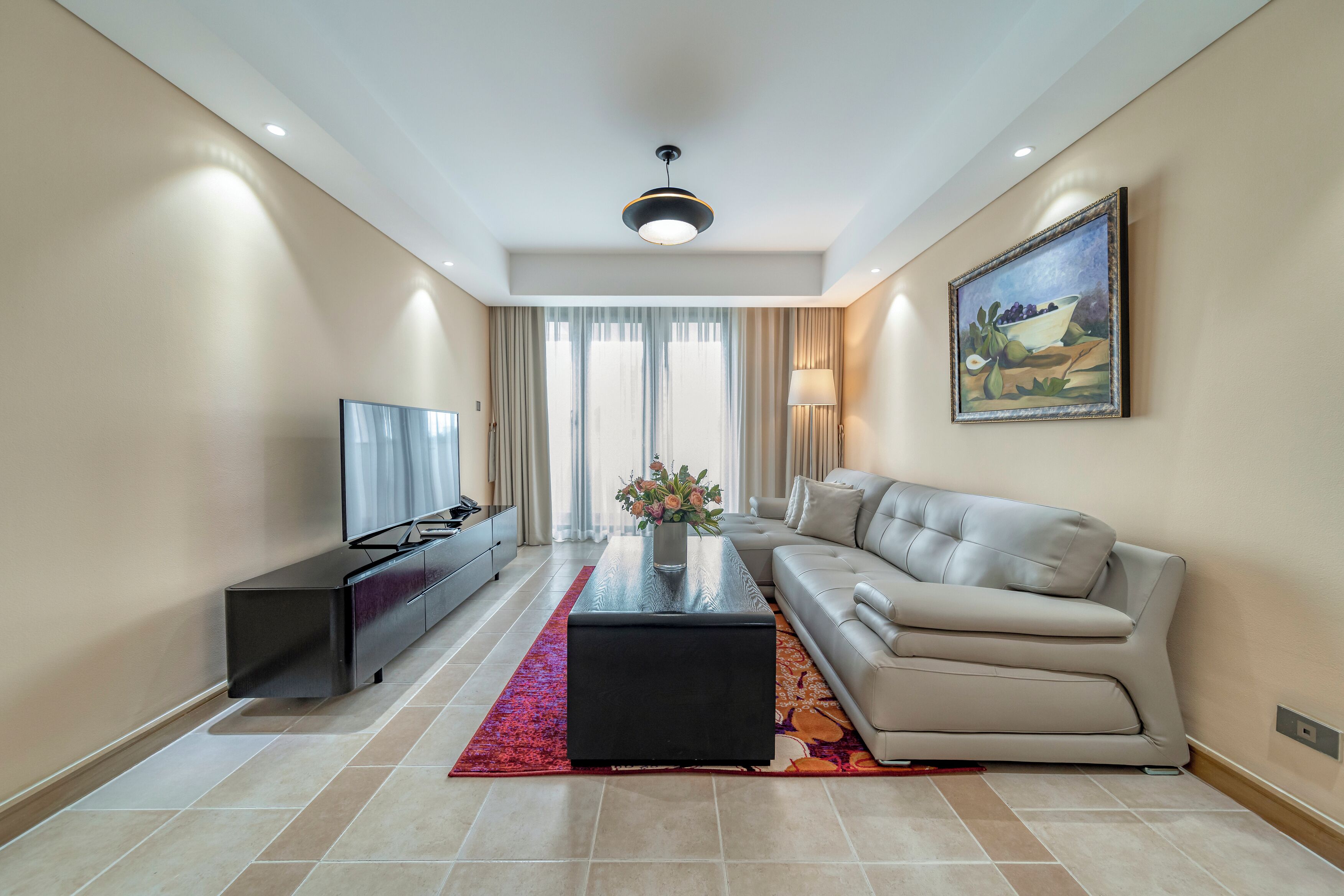 A modern living room with a sofa, a coffee table, a TV, and a painting on the wall.