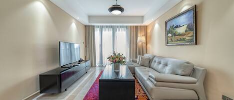 A modern living room with a sofa, a coffee table, a TV, and a painting on the wall.