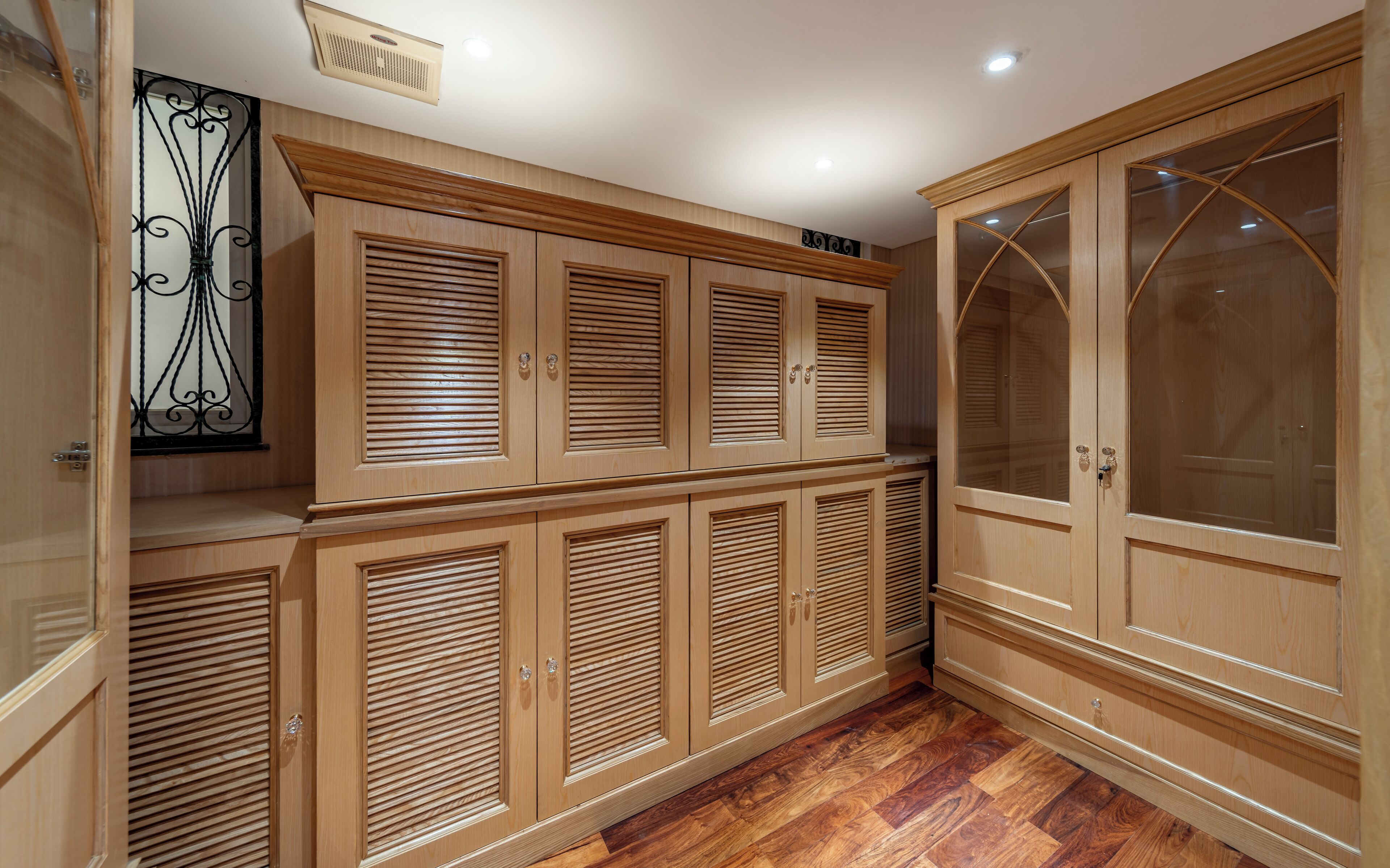 A room with wooden cabinets and a large arched glass door.