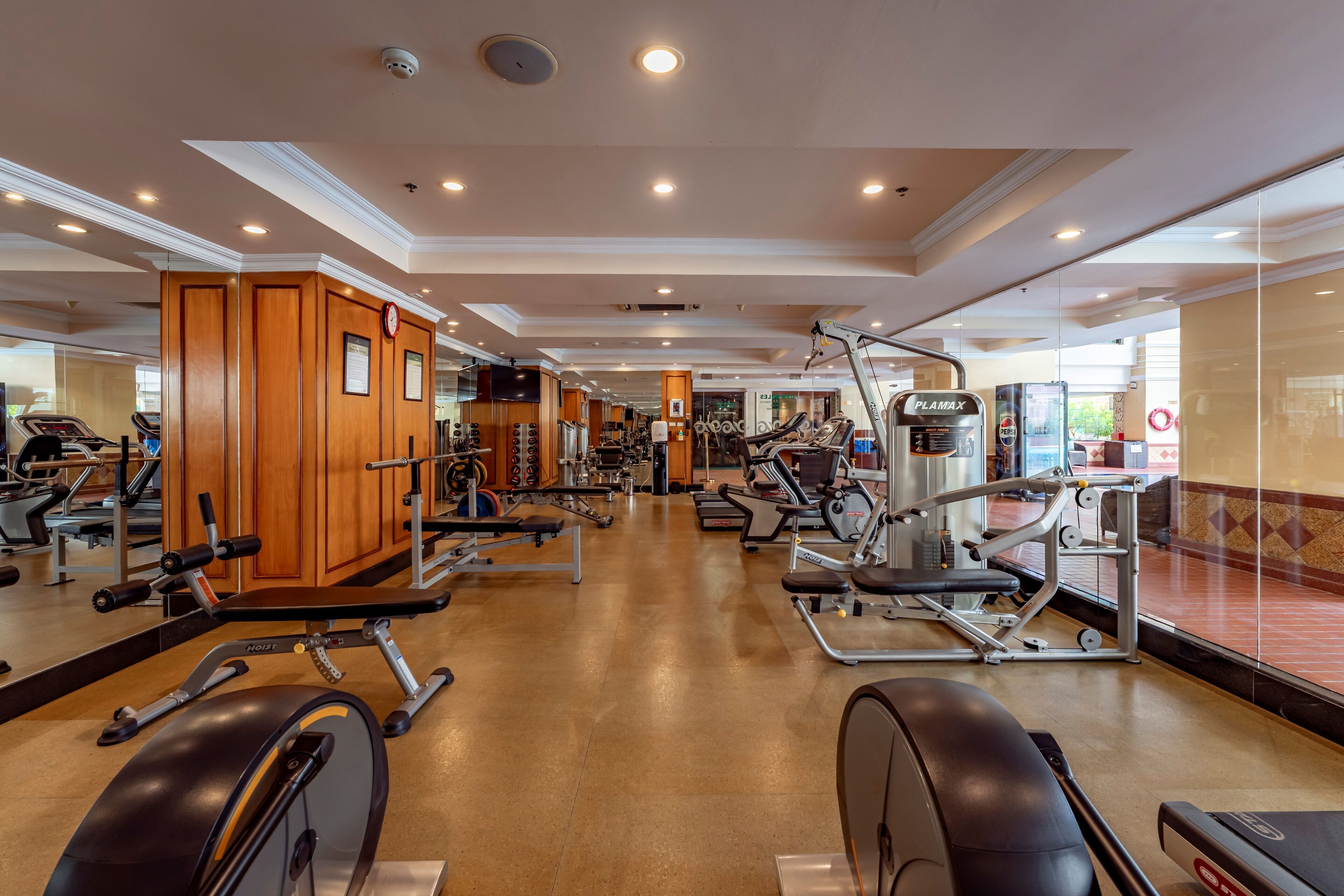 A gym with various exercise equipment, wooden cabinets, and a mirrored wall.