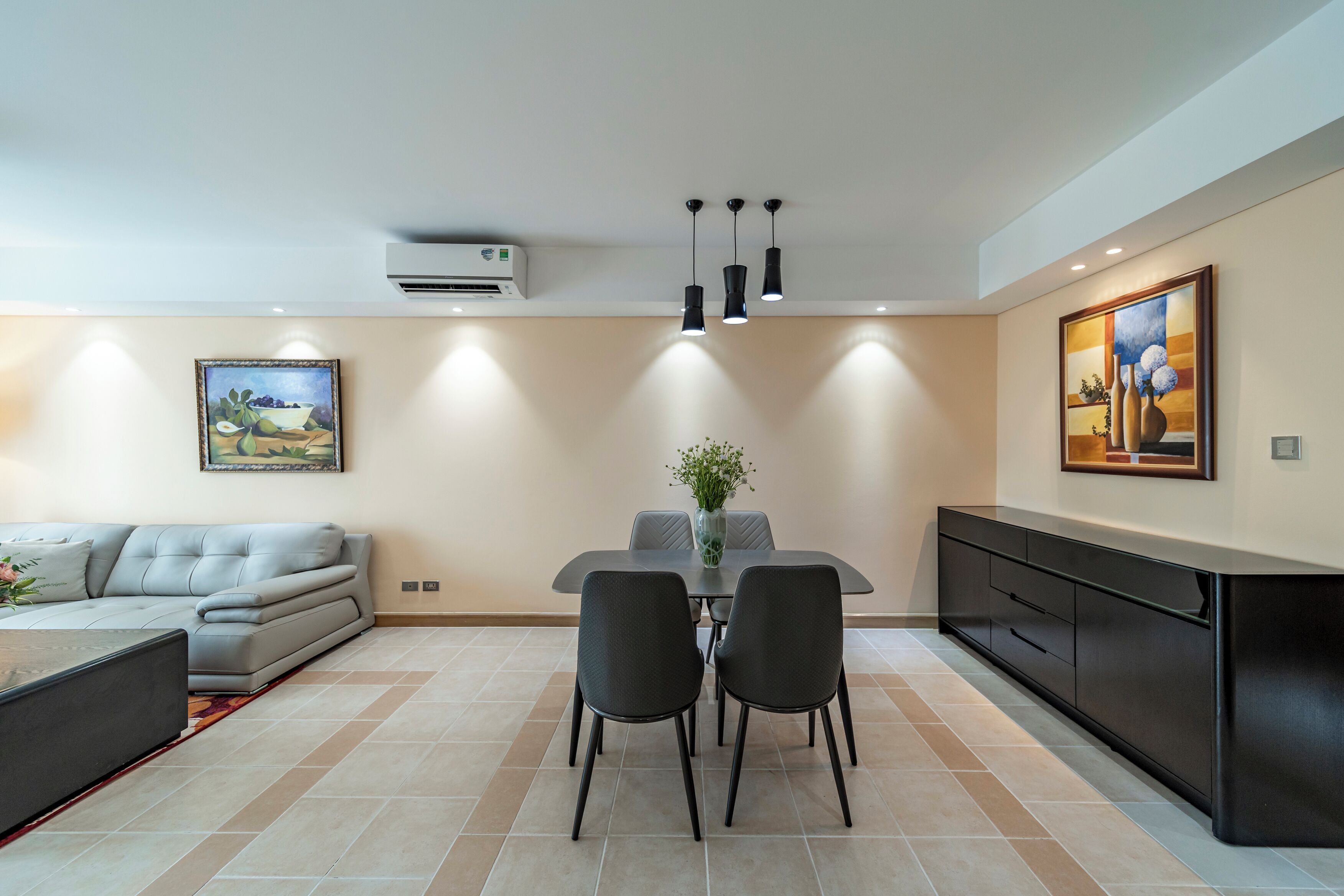 Una sala de estar moderna con un sofá gris, una mesa de comedor con sillas y una cocina con armarios y encimera.