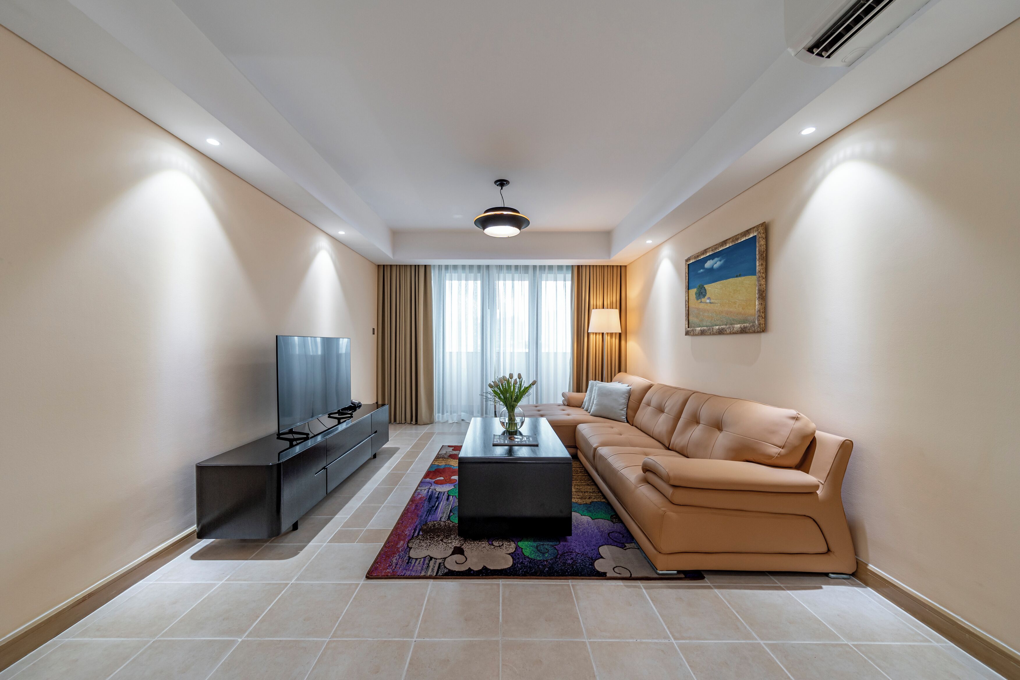 A modern living room with a sofa, a coffee table, a TV, and a painting on the wall.