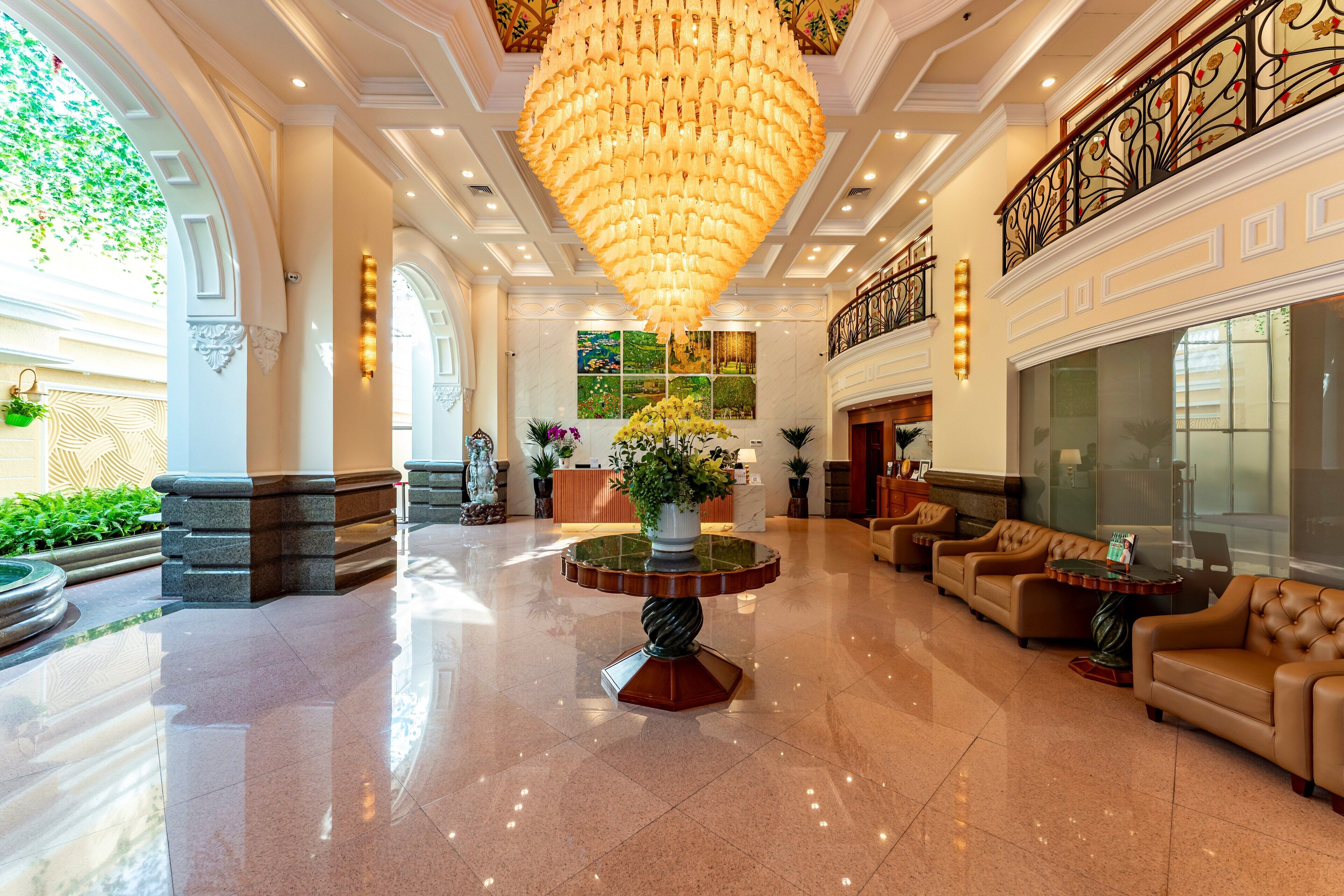 A spacious lobby with a large chandelier, comfortable seating, and a reception desk.