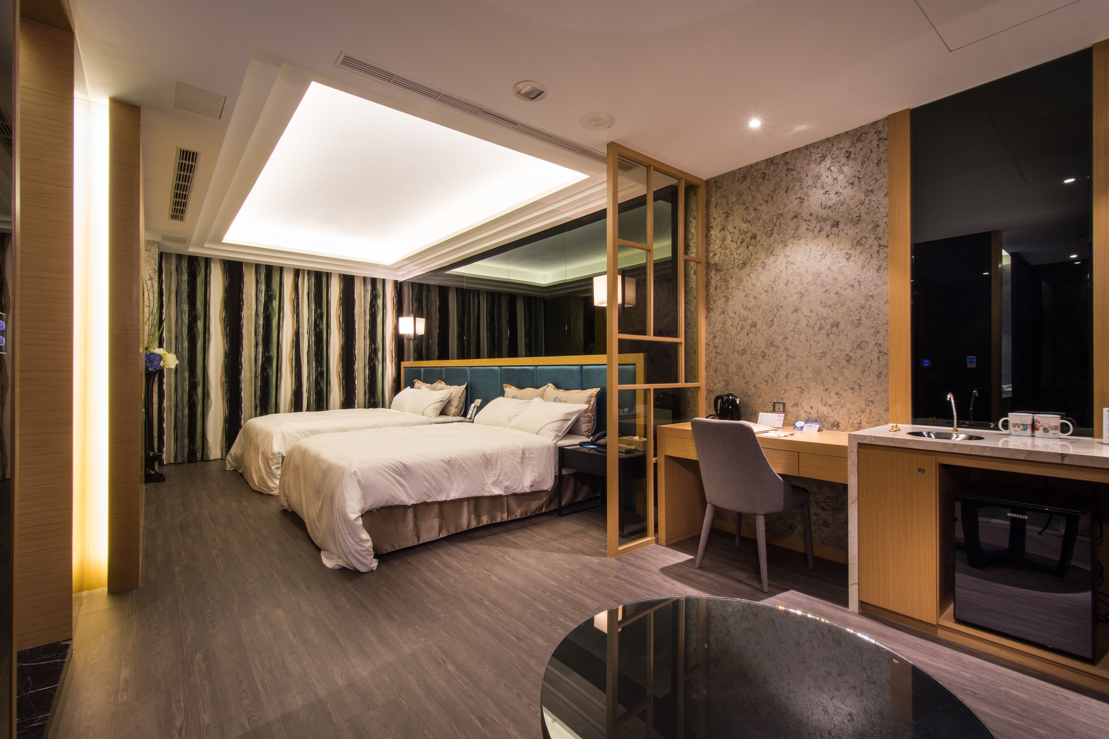 A modern hotel room with a large bed, a desk, and a built-in wardrobe.