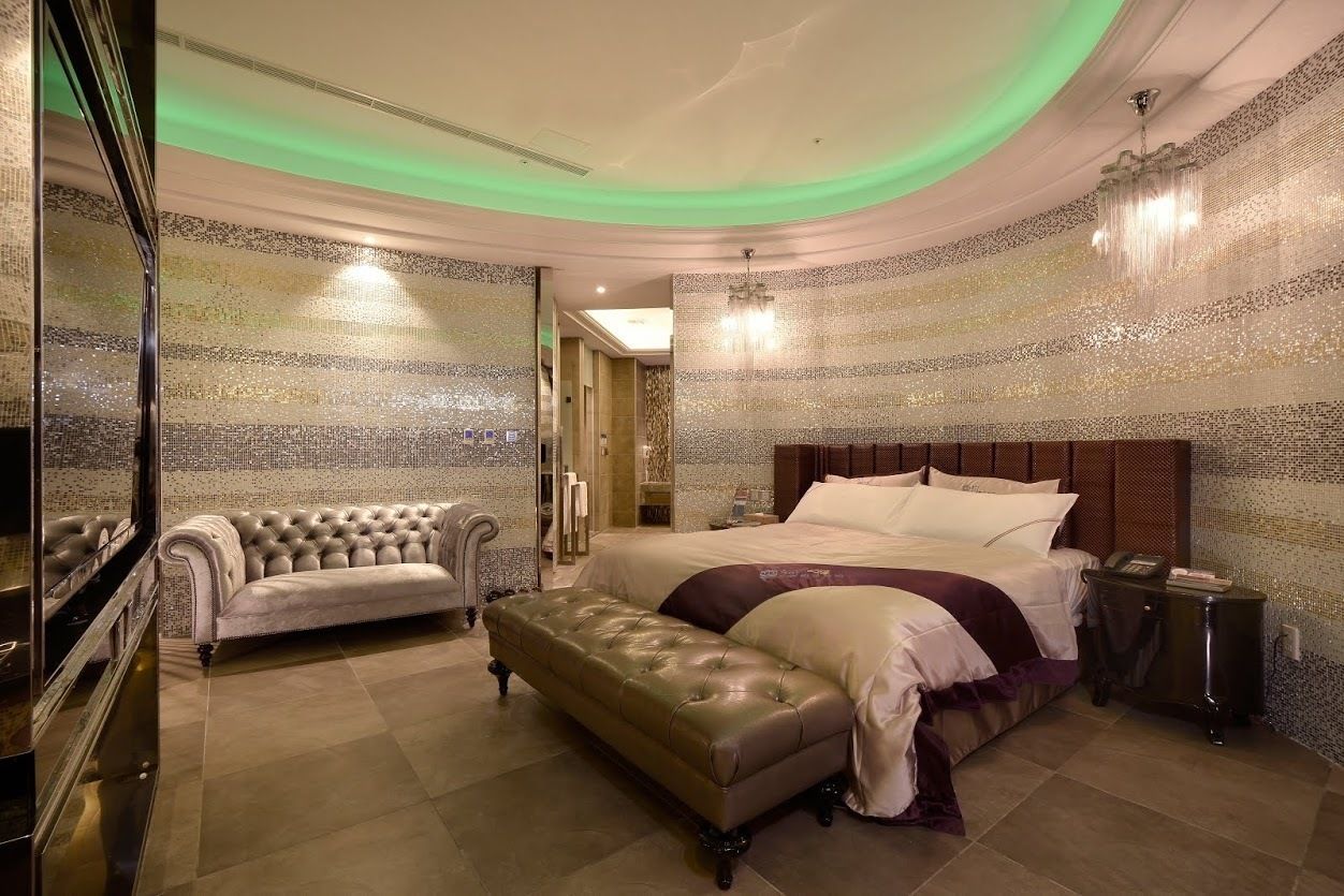 A luxurious bedroom with a large bed, a chaise lounge, and a bench.