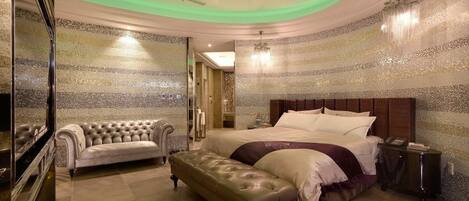 A luxurious bedroom with a large bed, a chaise lounge, and a bench.