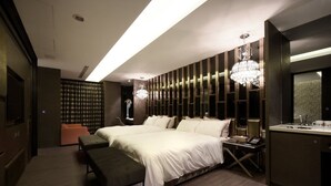 Een moderne hotelkamer met een groot bed, een bankje, een bureau en een kaptafel met spiegel.