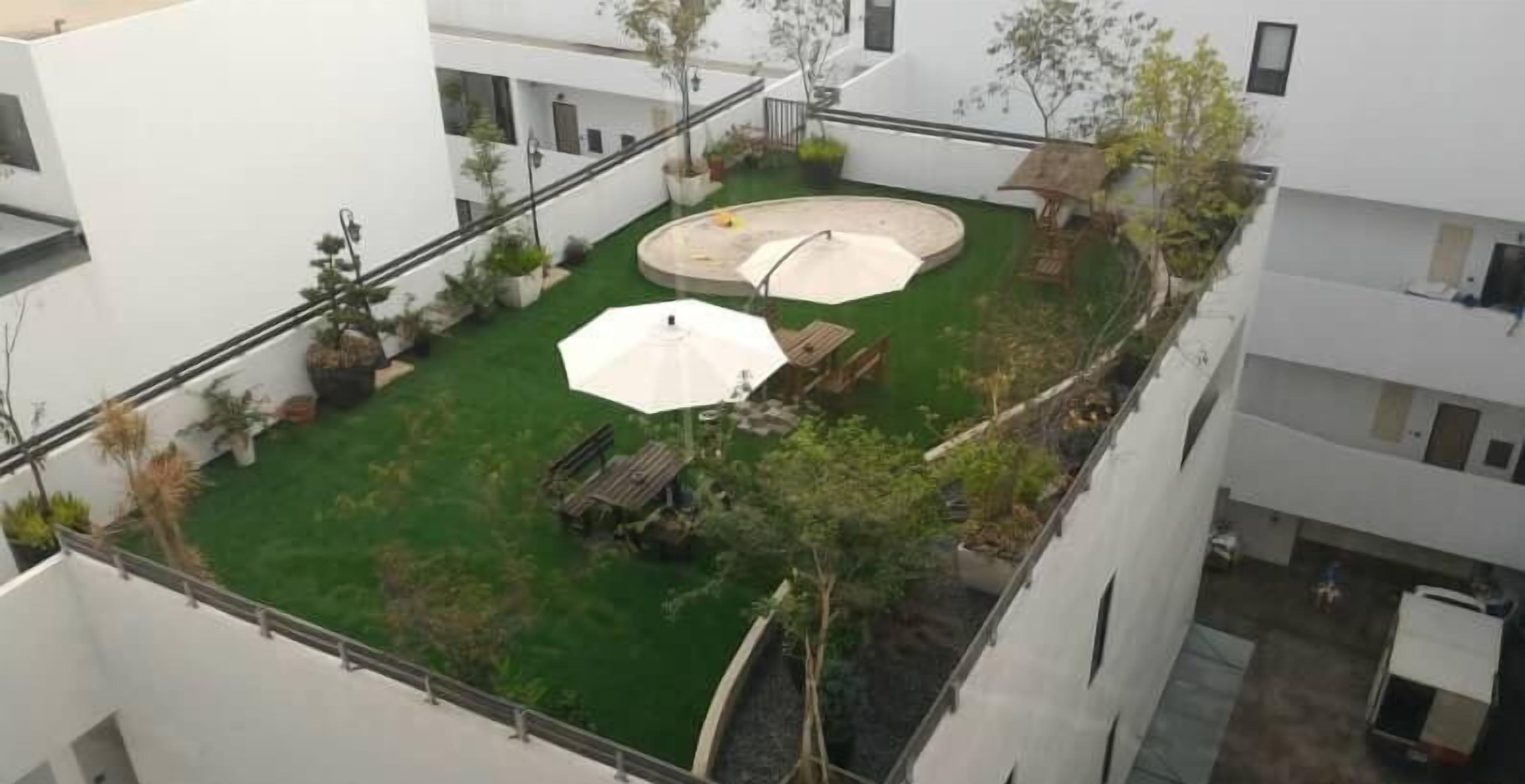 A rooftop garden with a circular seating area, a small pool, and potted plants.
