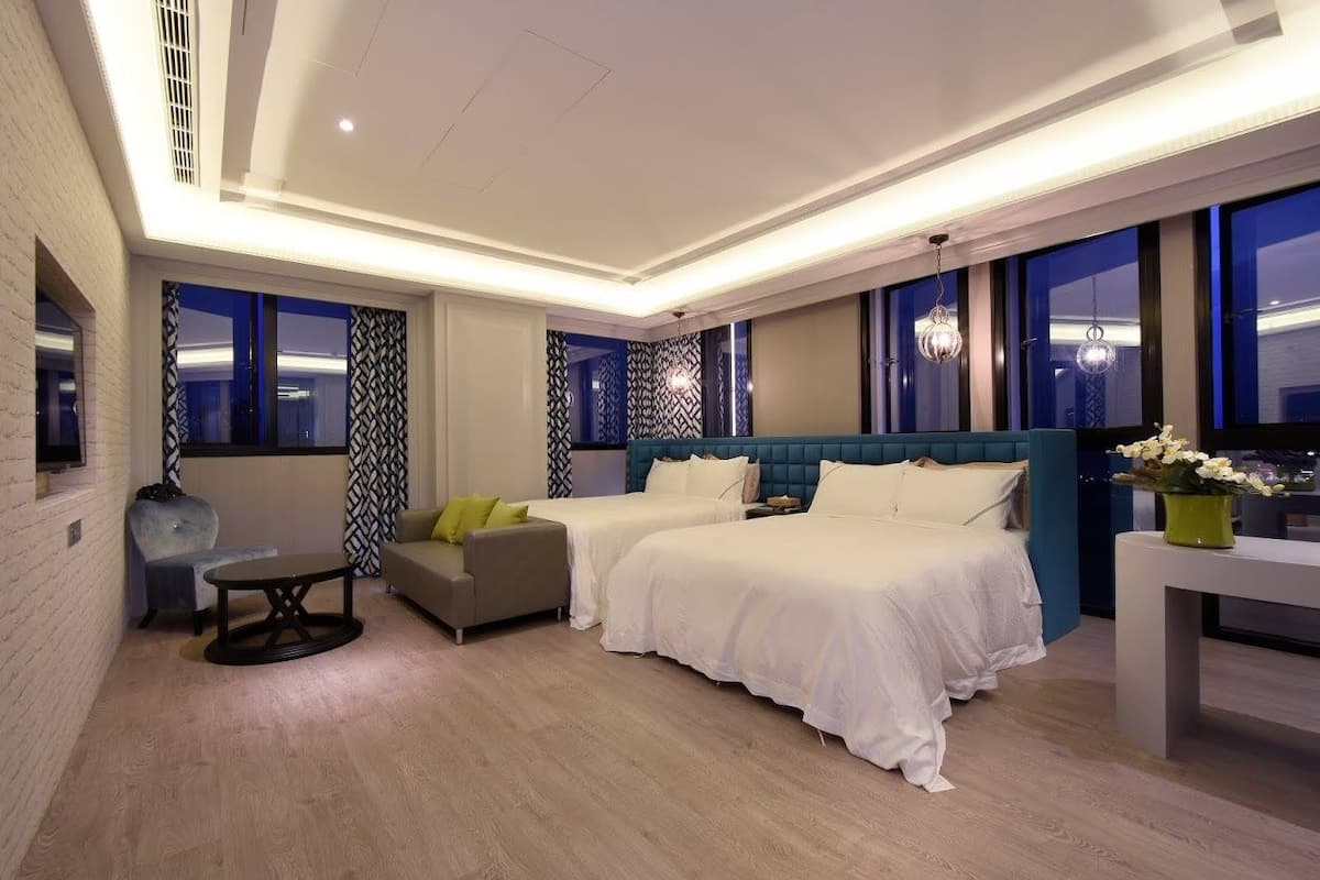 Een moderne hotelkamer met twee bedden, een bank, een klein tafeltje en een televisie.