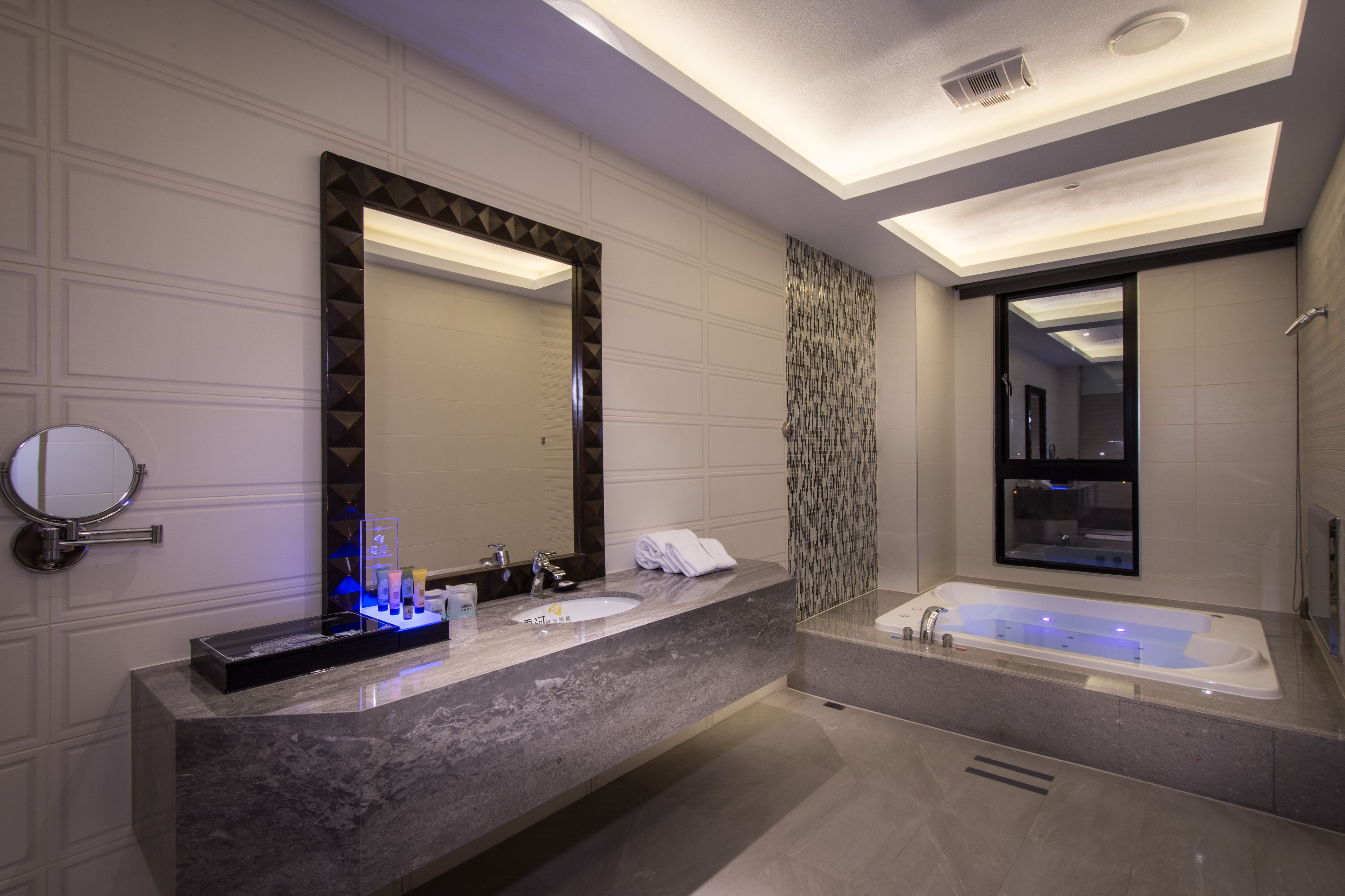 A modern bathroom with a large mirror, a vanity with a sink, and a separate bathtub.