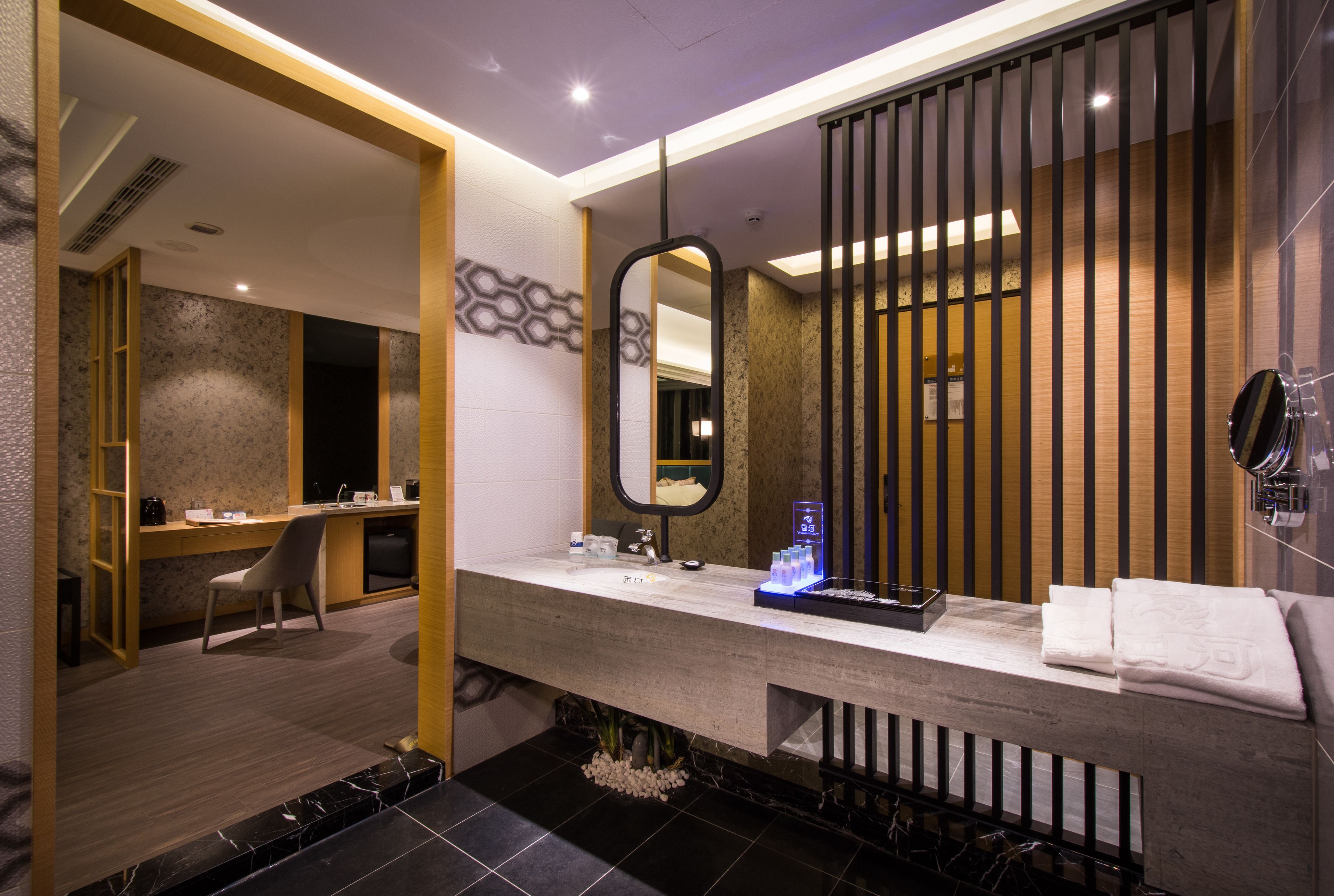 A modern bathroom with a large mirror, a vanity with a sink, and a shower area.
