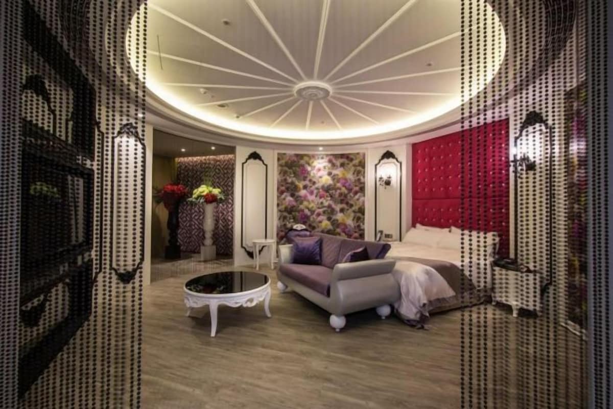 Una habitación con techo abovedado, un sofá, una mesa de centro y un papel tapiz floral.
