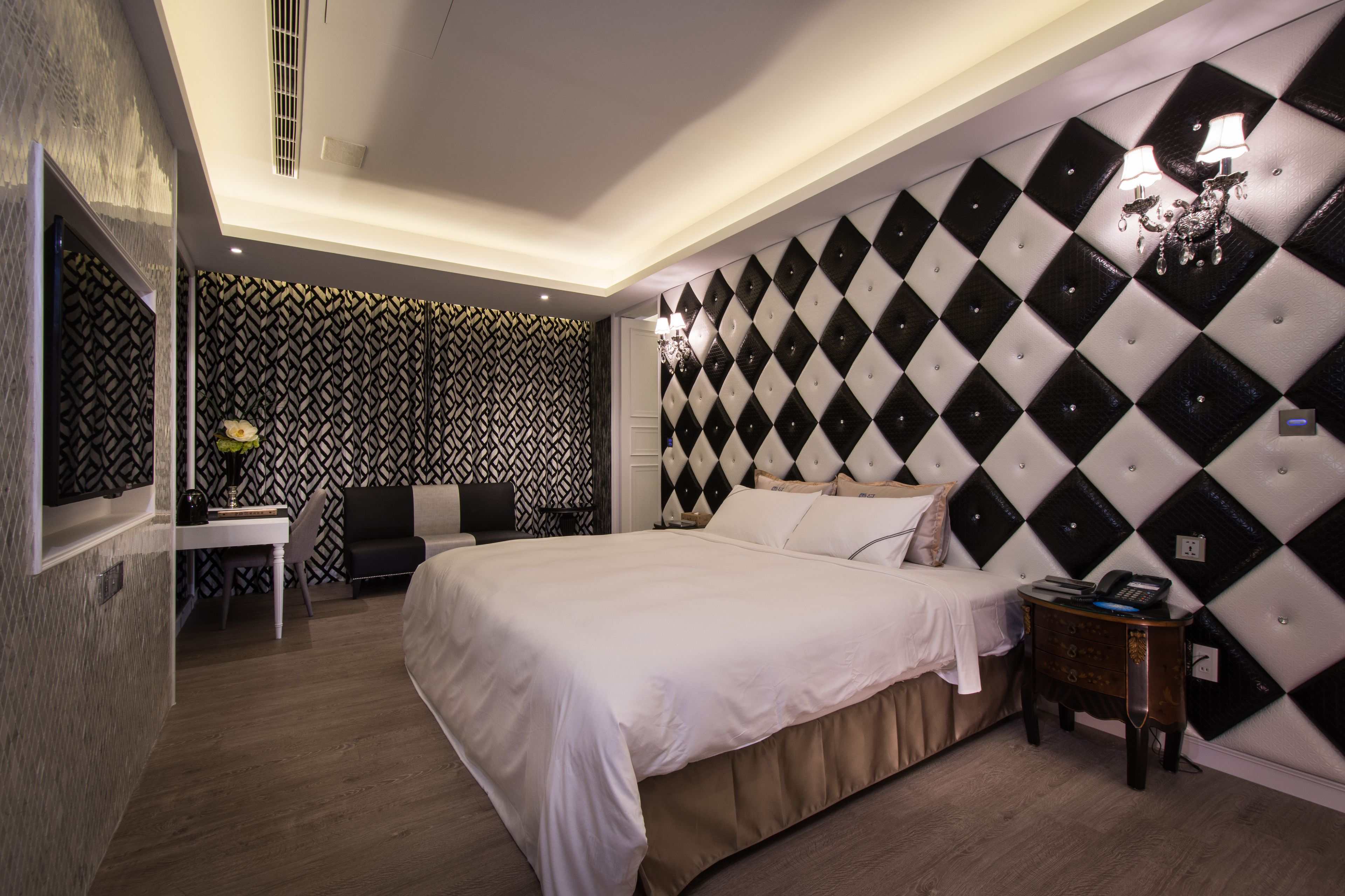 A modern bedroom with a large bed, a desk, and a chair.