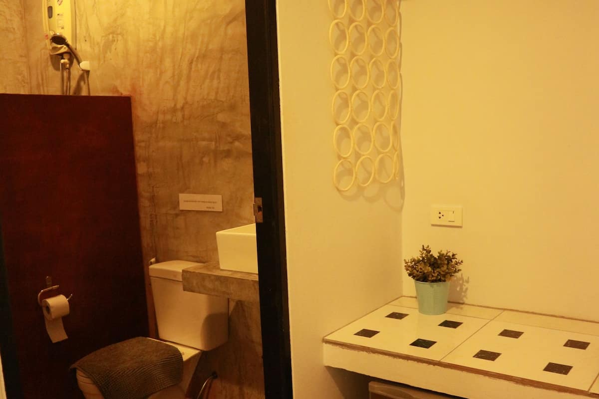 Baño pequeño y funcional con inodoro, lavamanos y un refrigerador compacto.