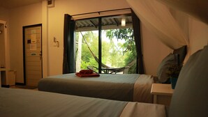 Ein Schlafzimmer mit zwei Betten, einem Fenster mit Blick auf Grünflächen, einer Tür mit einem Schild und einem kleinen Tisch mit einer Pflanze.