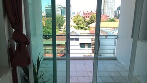 Un balcon offrant une vue sur le paysage urbain, avec ses bâtiments et sa végétation.
