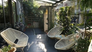 Um deck de madeira com cadeiras de vime branco e plantas em vasos.