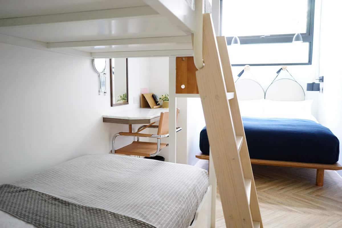 A compact bedroom with a bunk bed, a desk, and a chair.