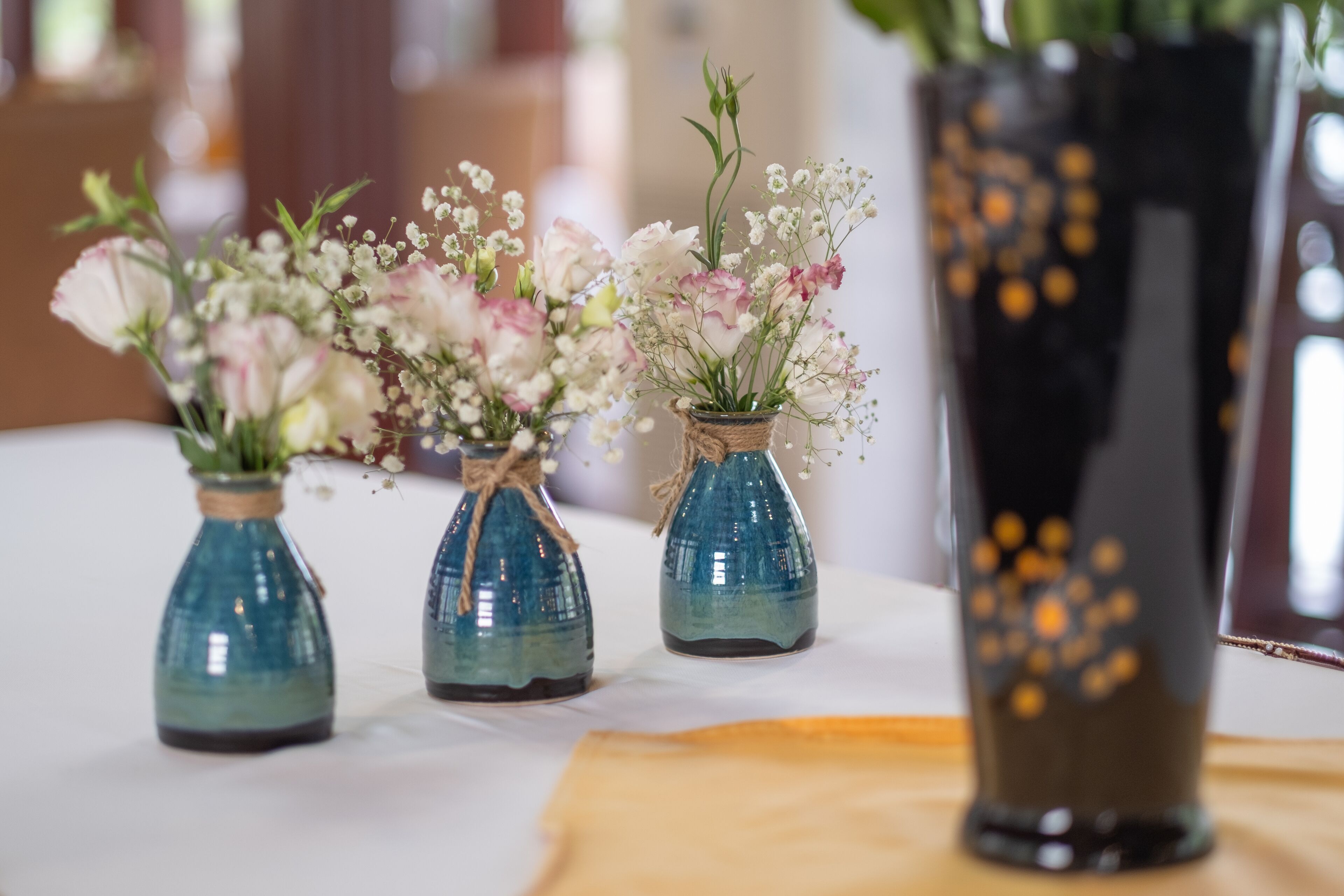 Three small blue glass vases with flowers on a table.