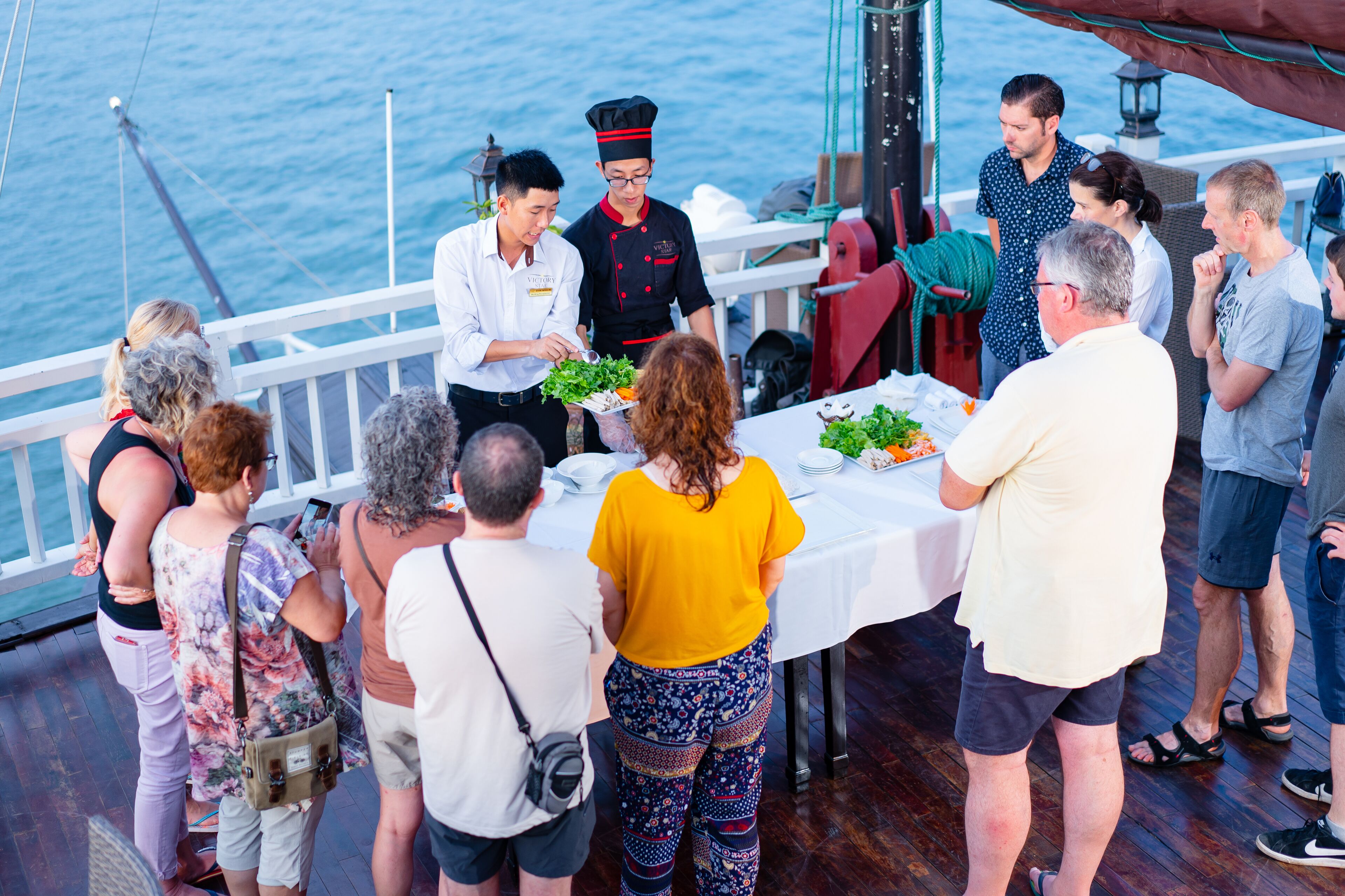 Un grupo de personas cenando en un barco con vistas al mar.