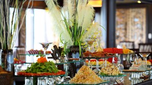 A buffet with various food items and a decorative plant with white feathers.