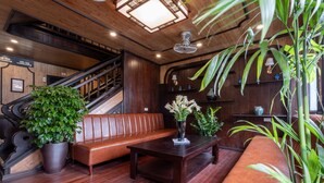 A wooden-floored lobby with a staircase, leather seating, a coffee table, and potted plants.