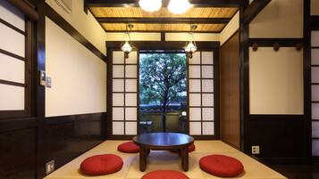 Una habitación tradicional japonesa con suelo de tatami, una mesa de madera baja y cojines rojos.