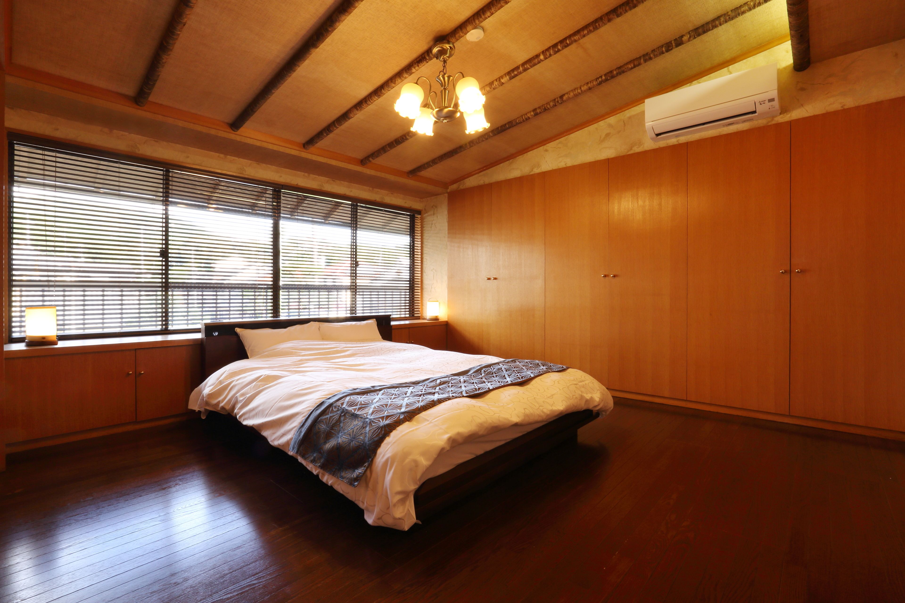 Une chambre à coucher avec un grand lit, une armoire en bois et un ventilateur de plafond.