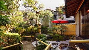 A traditional Japanese garden with a stone lantern, bamboo walkway, and a red umbrella. - Kyo-machiya Stay WAKA Fushimiinari-tei (Kyoto)