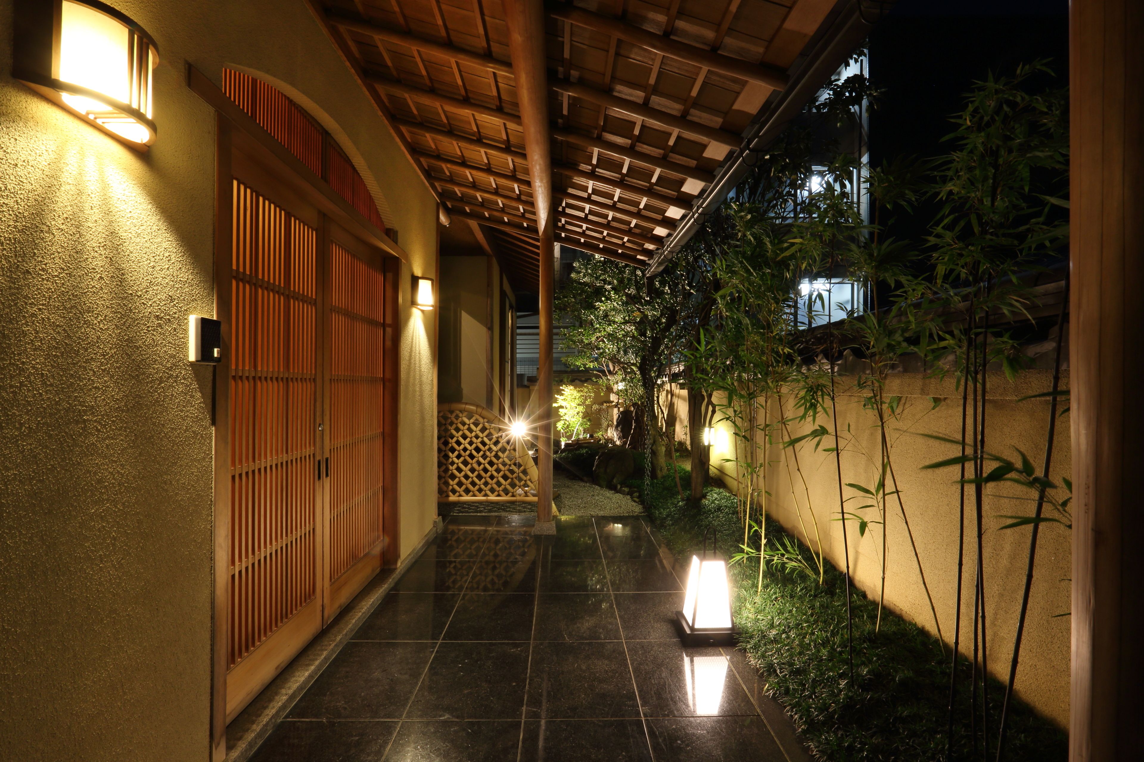A corridor with tiled flooring, wooden doors, and wall-mounted lights.