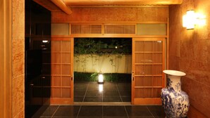 A traditional Japanese entrance with sliding doors, a tiled floor, and a large ceramic vase. - Kyo-machiya Stay WAKA Fushimiinari-tei (Kyoto)