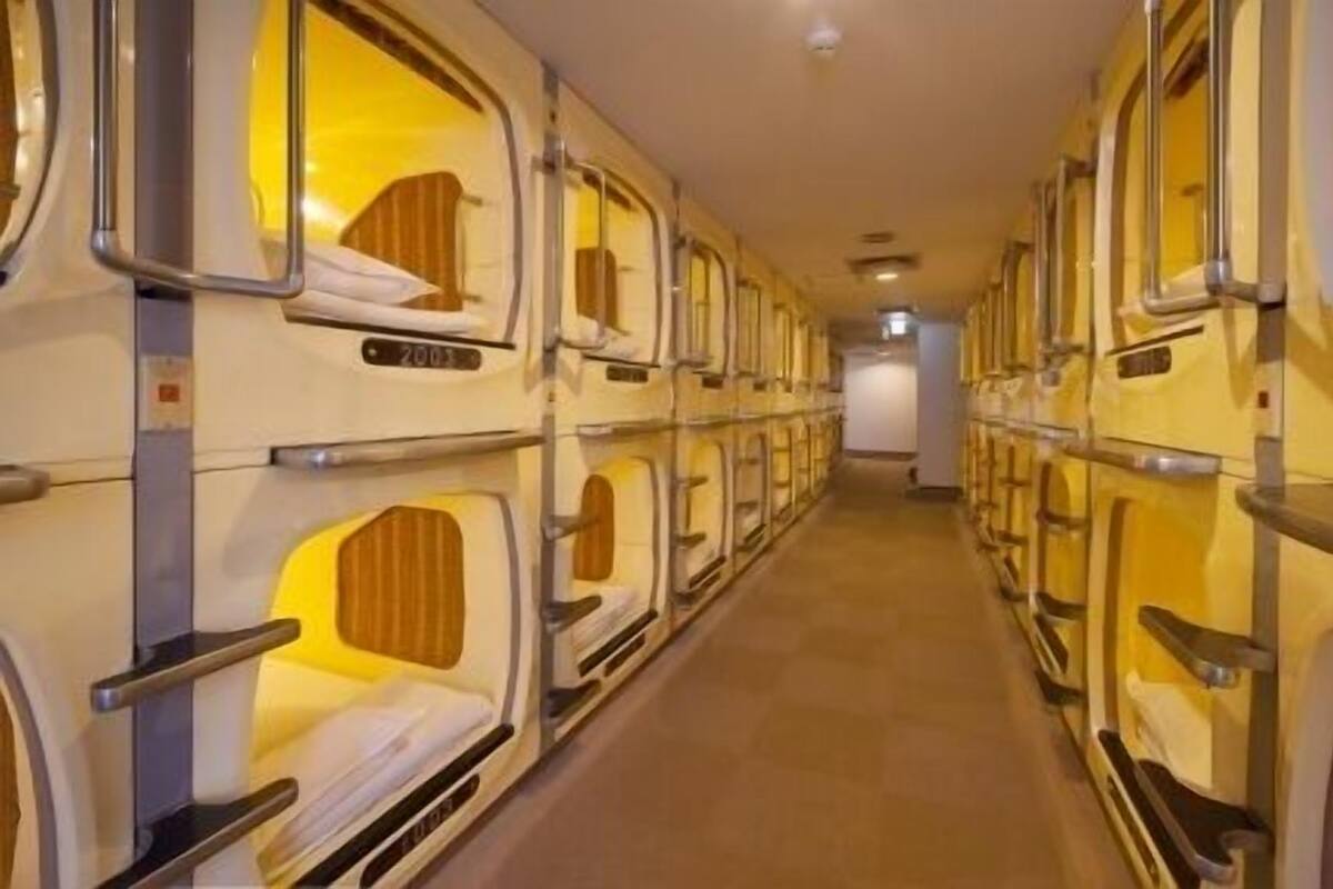 A row of bunk beds with individual headboards and footrests, arranged in a corridor.