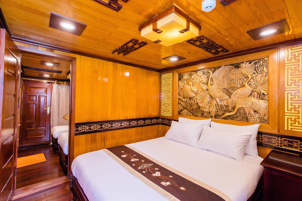 A traditional wooden room with a large bed, a decorative wall carving, and a wooden door.