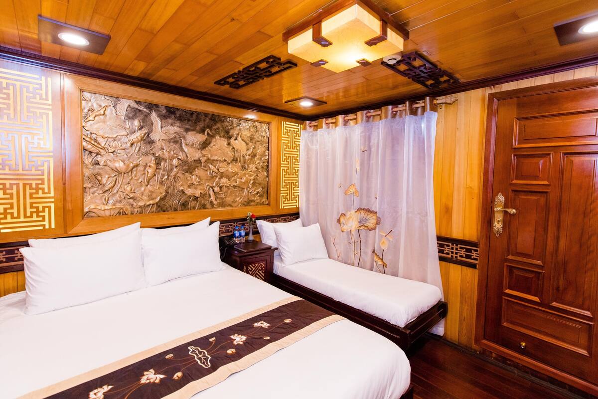 A hotel room with two beds, a wooden ceiling, a decorative wall, and a traditional door.