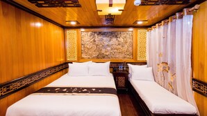 Habitación de hotel con dos camas, paneles de madera, un adorno en la pared y una cortina al estilo chino tradicional.