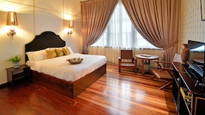 Une chambre d’hôtel avec un grand lit, un bureau en bois, une chaise et un téléviseur.