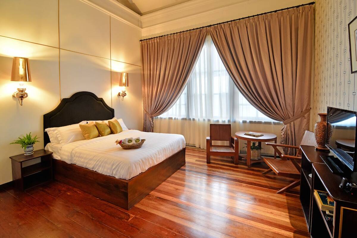 Une chambre d’hôtel avec un grand lit, un bureau en bois, une chaise et un téléviseur.