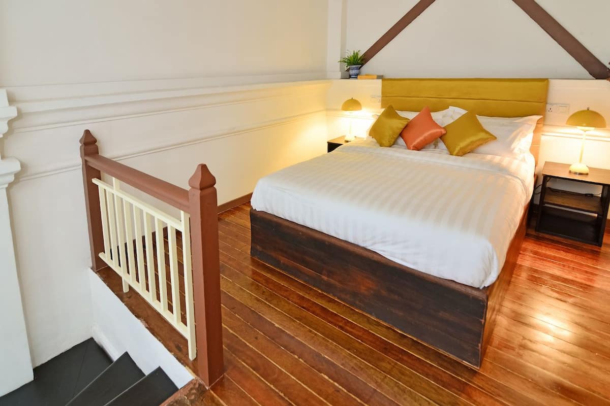Une chambre à coucher avec un lit en bois, une literie blanche et deux tables de chevet avec des lampes.