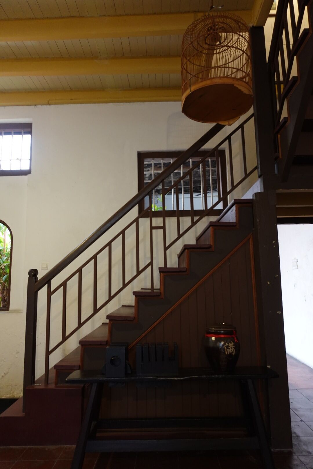 A staircase with wooden steps and a metal railing, leading to an upper floor.